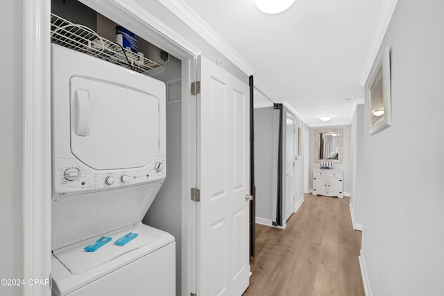 laundry room with stacked washer and dryer, laundry area, baseboards, light wood-style flooring, and crown molding