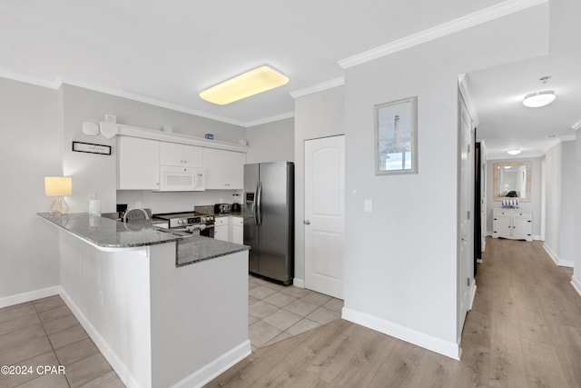 kitchen featuring dark stone countertops, a peninsula, stainless steel appliances, crown molding, and white cabinetry