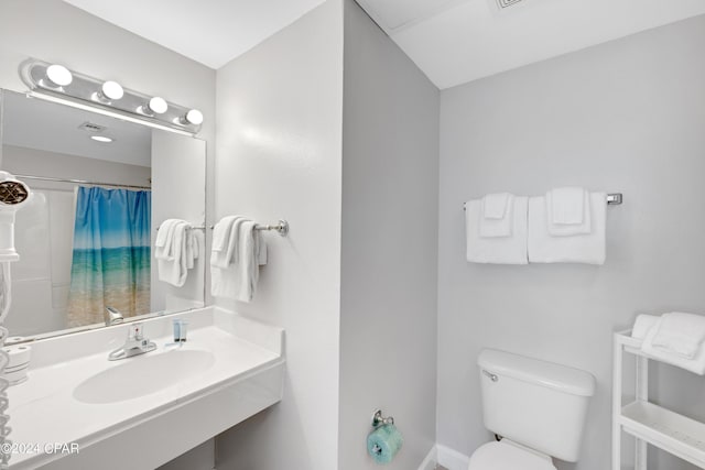 bathroom featuring a shower with shower curtain, a sink, and toilet