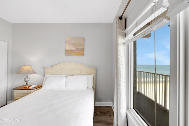 bedroom with a water view, baseboards, and wood finished floors