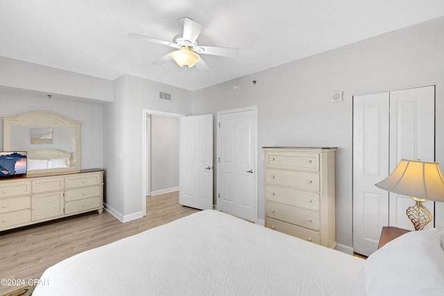 bedroom with a ceiling fan, visible vents, baseboards, and wood finished floors