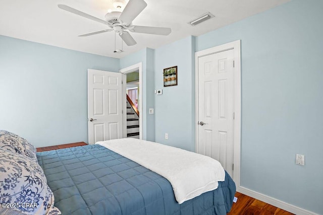 bedroom featuring a ceiling fan, visible vents, dark wood finished floors, and baseboards