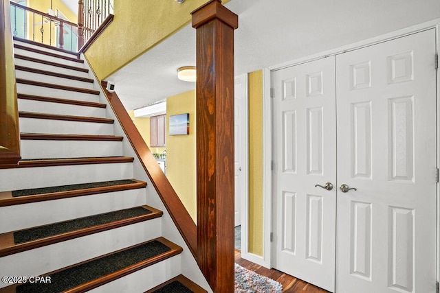 staircase featuring wood finished floors and ornate columns