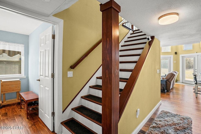 stairway featuring a textured ceiling, hardwood / wood-style flooring, and baseboards