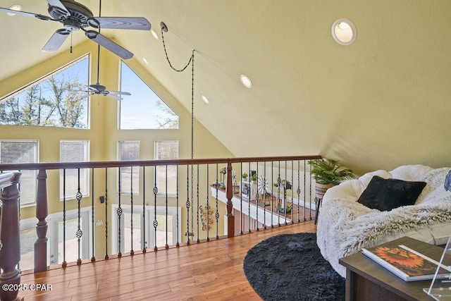 living area with ceiling fan, high vaulted ceiling, and wood finished floors