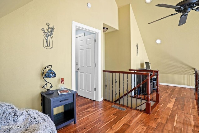 interior space featuring baseboards, visible vents, an upstairs landing, and wood finished floors