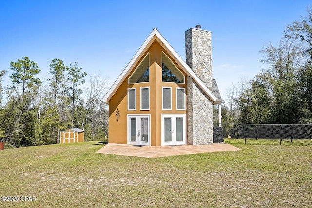 rear view of house with a yard, fence, a patio, and french doors