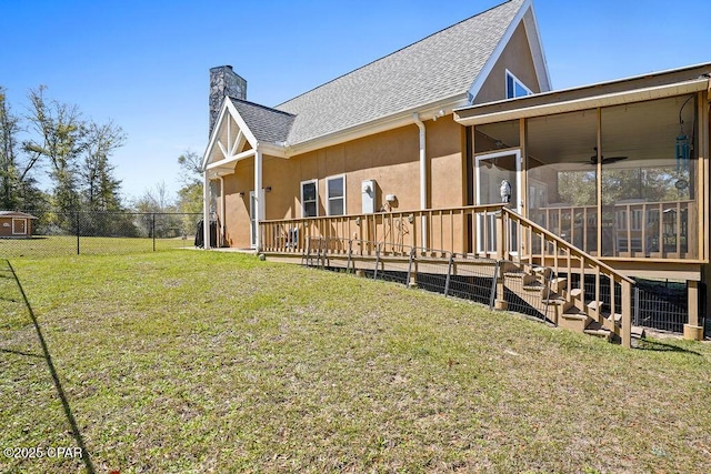 rear view of property featuring a sunroom, a chimney, fence, a yard, and stucco siding