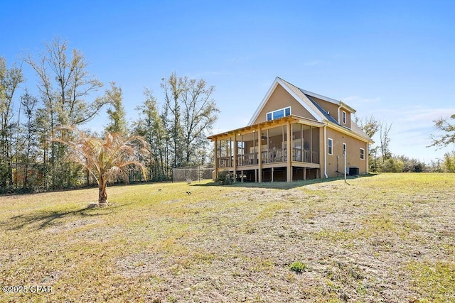 rear view of property with central air condition unit, a sunroom, and a yard