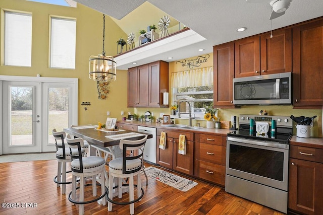 kitchen featuring a sink, french doors, appliances with stainless steel finishes, dark wood-style floors, and pendant lighting