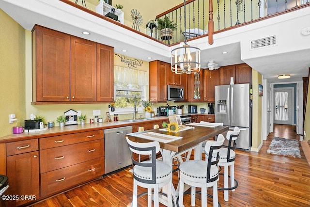 kitchen with dark wood-style floors, visible vents, stainless steel appliances, and a sink