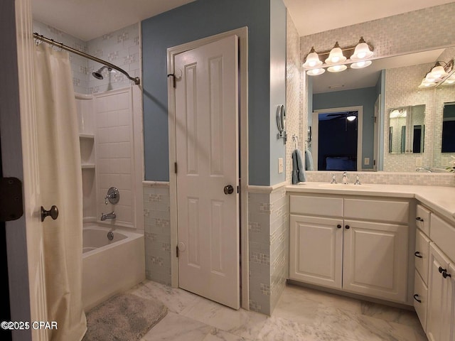 full bathroom with shower / bath combo, tile walls, a wainscoted wall, marble finish floor, and vanity