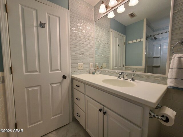 bathroom with vanity, tile walls, and visible vents
