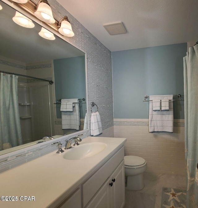 full bath featuring tile walls, toilet, vanity, a shower with curtain, and wainscoting