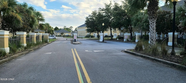 view of road with a gate, curbs, a gated entry, street lights, and a residential view