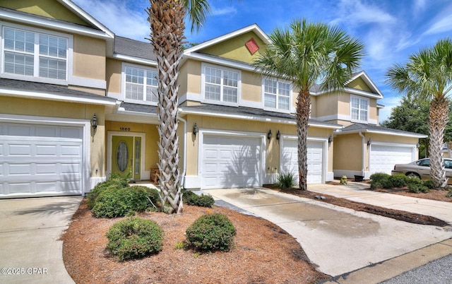 view of property featuring a shingled roof, driveway, stucco siding, and a garage