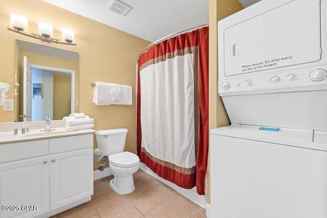 bathroom with tile patterned flooring, toilet, stacked washer / dryer, vanity, and visible vents