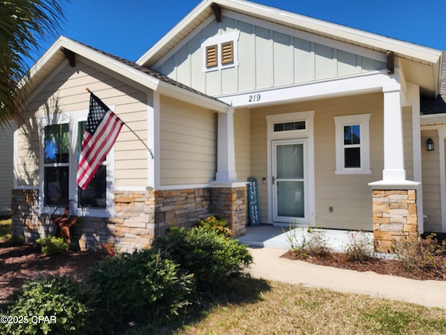 property entrance with stone siding, a porch, and board and batten siding