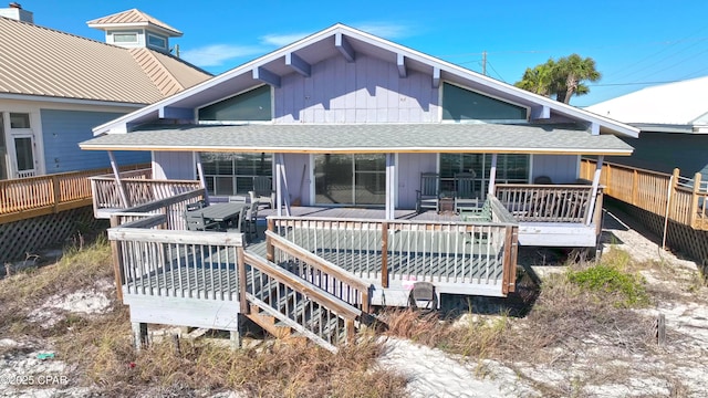 view of front of home featuring a shingled roof, a deck, and fence