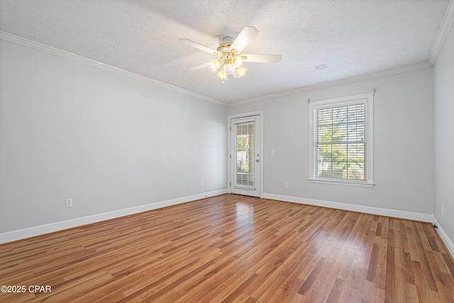 spare room with a textured ceiling, light wood finished floors, baseboards, and crown molding