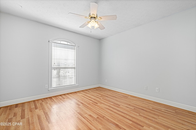 empty room featuring a textured ceiling, light wood finished floors, a ceiling fan, and baseboards