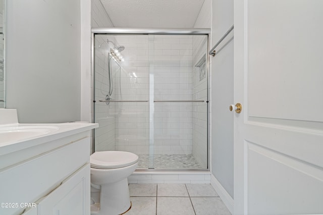 bathroom featuring toilet, a stall shower, vanity, a textured ceiling, and tile patterned flooring