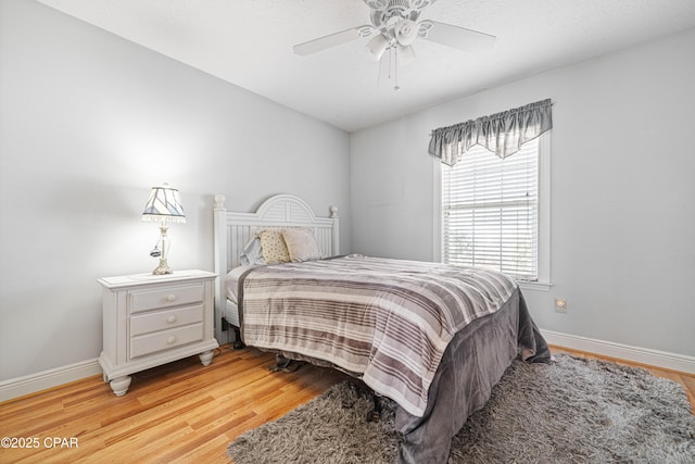 bedroom with a ceiling fan, baseboards, and light wood finished floors