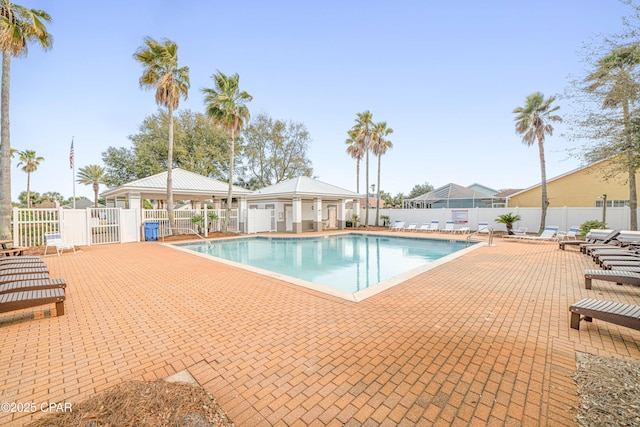 community pool with a patio area, fence, and a gazebo