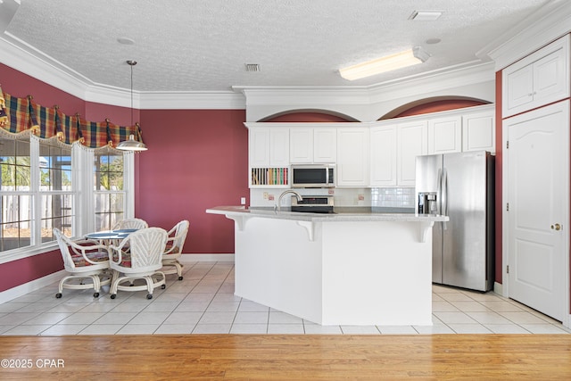 kitchen featuring light tile patterned flooring, stainless steel appliances, white cabinetry, visible vents, and a kitchen breakfast bar