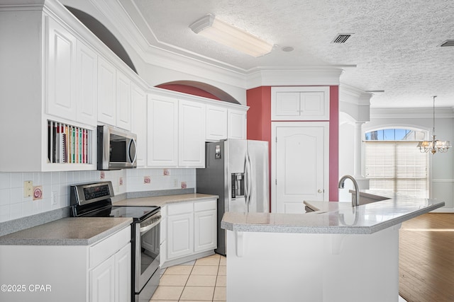 kitchen with visible vents, an inviting chandelier, appliances with stainless steel finishes, light tile patterned flooring, and white cabinetry