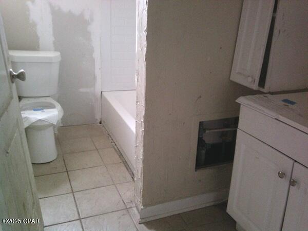 full bathroom featuring tile patterned floors, toilet, and a tub