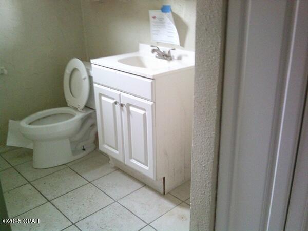 half bath with toilet, vanity, and tile patterned flooring