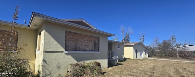 view of side of home featuring stucco siding, a garage, and an outdoor structure