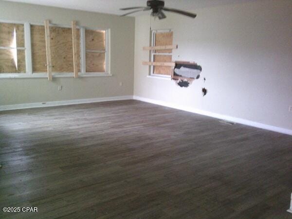 unfurnished room with ceiling fan, baseboards, and dark wood finished floors