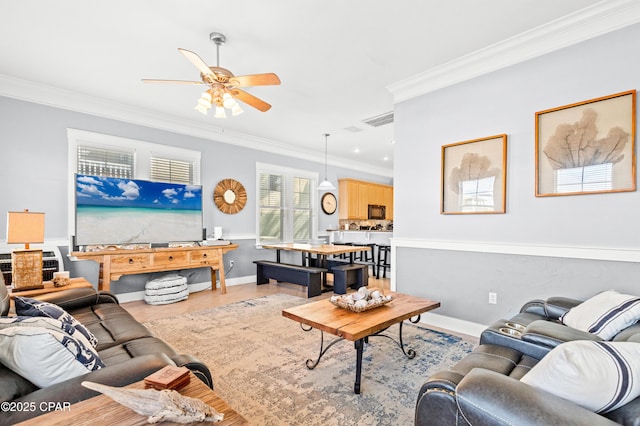 living room featuring baseboards, ornamental molding, visible vents, and a ceiling fan