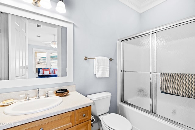 bathroom featuring visible vents, toilet, ornamental molding, combined bath / shower with glass door, and vanity