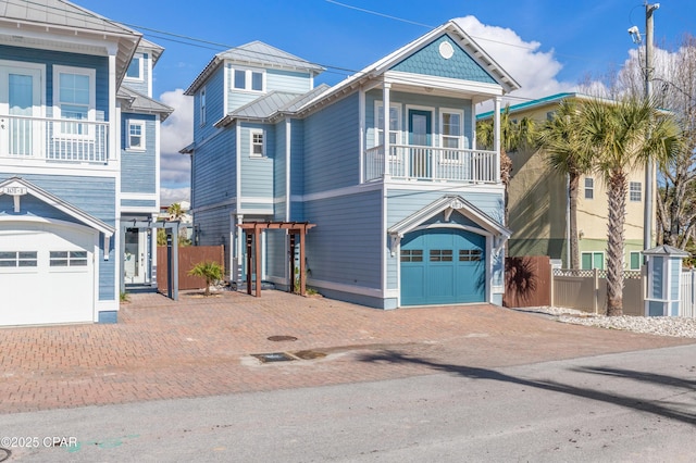 raised beach house with metal roof, a garage, fence, decorative driveway, and a standing seam roof