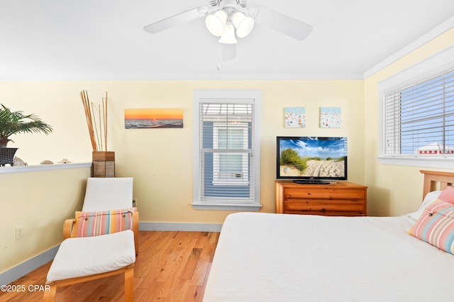 bedroom with crown molding, ceiling fan, wood finished floors, and baseboards