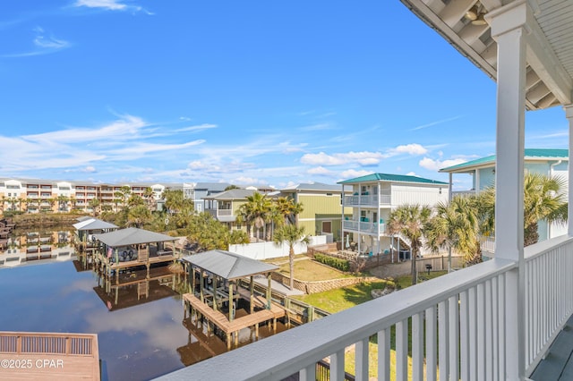 balcony featuring a dock, a water view, boat lift, and a residential view