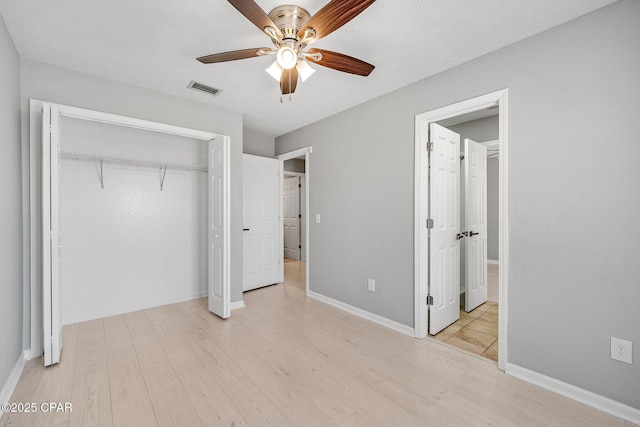 unfurnished bedroom with a closet, visible vents, light wood-style flooring, a ceiling fan, and baseboards