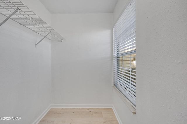 walk in closet with light wood finished floors