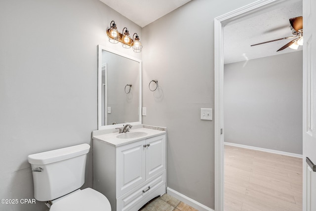 bathroom with baseboards, a ceiling fan, toilet, wood finished floors, and vanity