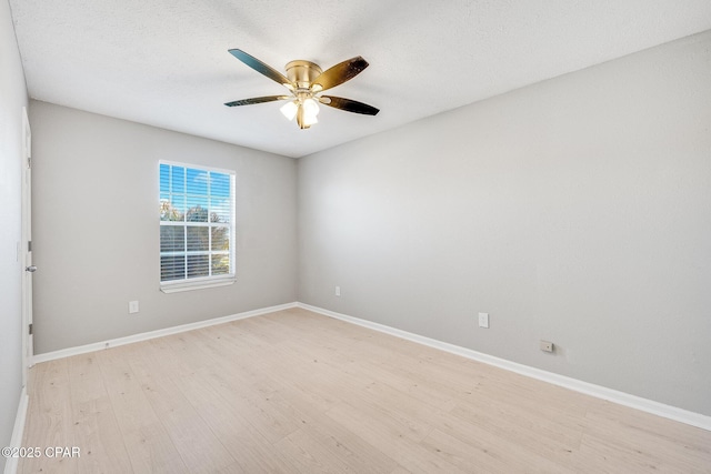 spare room featuring a ceiling fan, light wood-style flooring, baseboards, and a textured ceiling