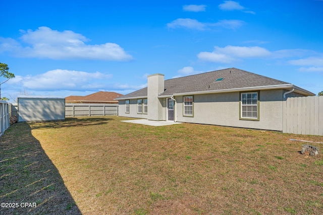 back of property with an outbuilding, a patio, a fenced backyard, a yard, and stucco siding