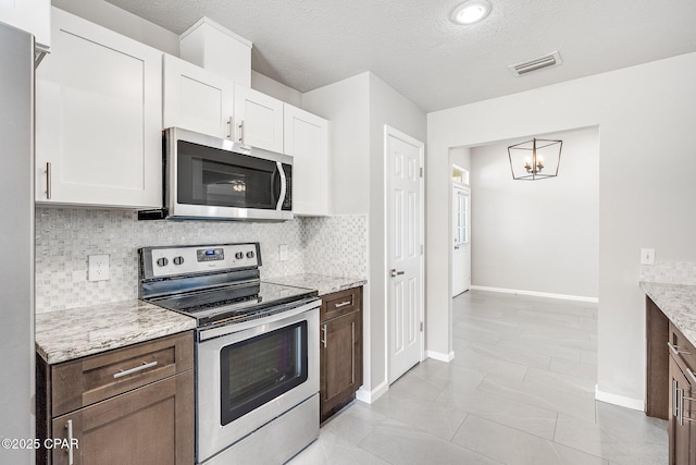 kitchen with stainless steel appliances, white cabinets, visible vents, and backsplash