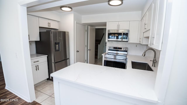 4305 Bay Point Rd Unit 459, Panama City, FL 32408 - kitchen with a peninsula, a sink, stainless steel appliances, white cabinetry, and light stone countertops