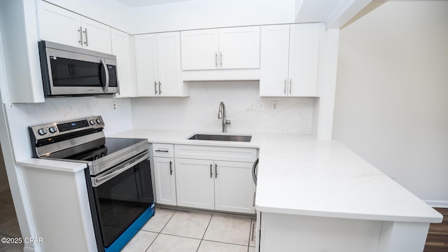 4305 Bay Point Rd Unit 459, Panama City, FL 32408 - kitchen featuring a sink, a peninsula, white cabinetry, and appliances with stainless steel finishes