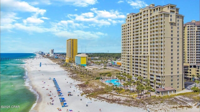 drone / aerial view featuring a water view, a view of city, and a beach view