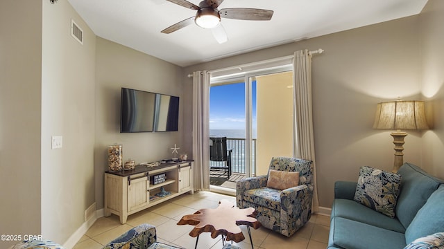 living area featuring light tile patterned floors, ceiling fan, visible vents, and baseboards