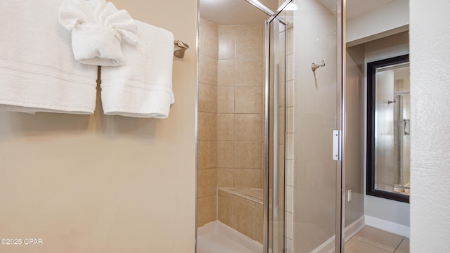 bathroom with tile patterned flooring, a shower stall, and baseboards